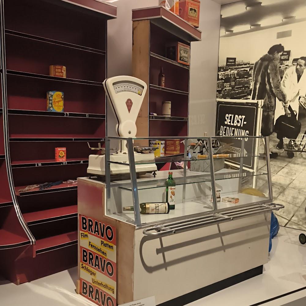 A vintage grocery store display with a scale and shelves. The sign reads